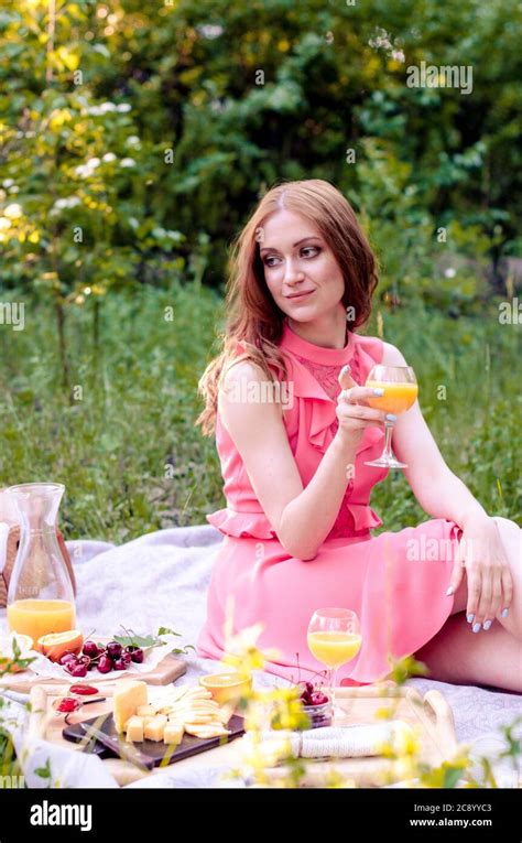Pretty Young Redhead Girl In Pink Dress Having Summer Picnic In Park
