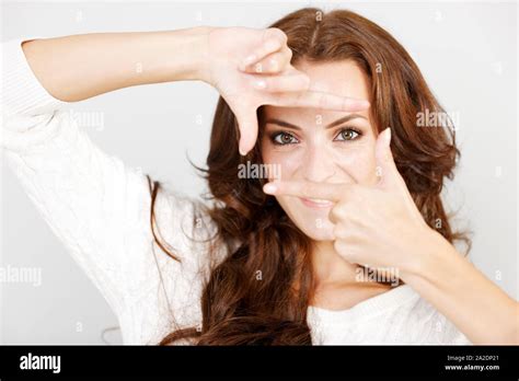 Beautiful Young Woman Holding Her Hands Up Like A Frame Around Her Eyes