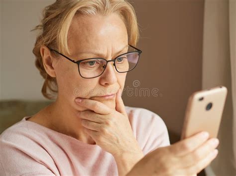 Upset Retired Woman Reading A News Feed On The Internet Looking At The Screen Of A Smartphone