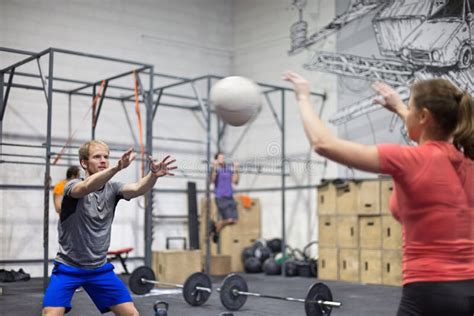 Man Throwing Medicine Ball Towards Woman In Crossfit Gym Stock Photo