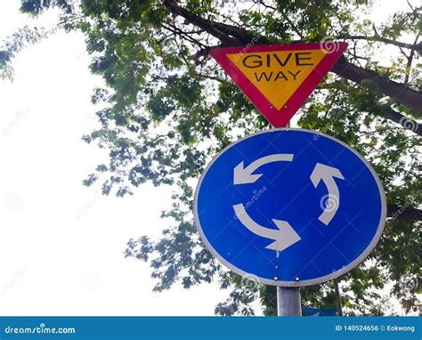 Give Way Road Sign With Blue And White Roundabout Symbol Stock Photo