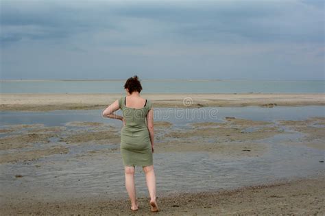Young Woman In Dress Is Standing In Front Of The Sea Stock Photo