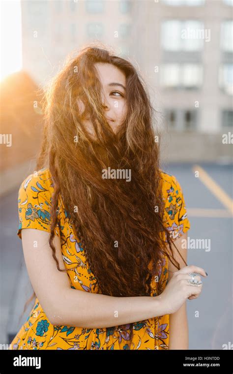 Portrait Of Young Girl Pulling Long Wavy Hair Across Face In Parking