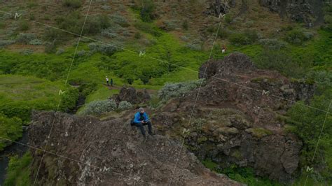 Aerial View Man Trekker Sitting Peak In Iceland Highlands Using Drone