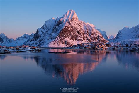 Snow Covered Olstind Mountain Peak Glows Pink In Winter Sunrise Reine