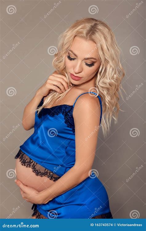 Happy Beautiful Blond Pregnant Woman Expecting Maternity Hugging Her Belly In Blue Lingerie