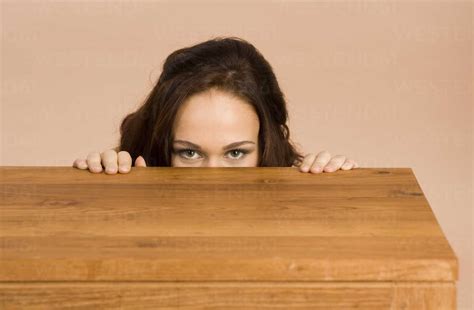 Young Woman Hiding Behind Table Stock Photo
