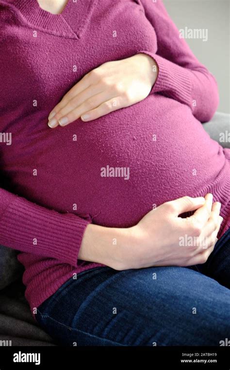 the belly of a caucasian woman pregnant in the seventh month of pregnancy mom wears a red