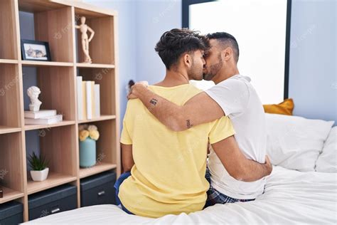 Couple De Deux Hommes Sembrassant Et Sembrassant Assis Sur Le Lit Dans La Chambre Photo Premium