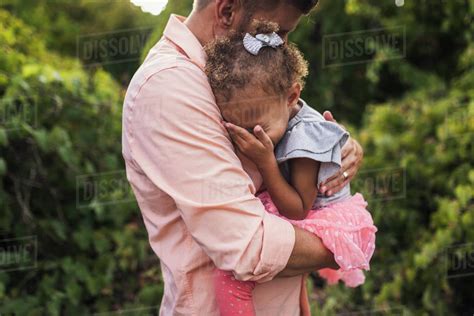 Side View Of Father Embracing Daughter While Standing Against Plants In