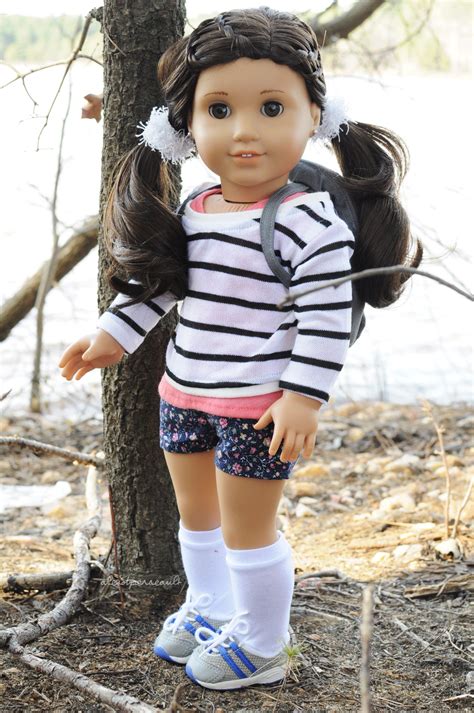 A Doll Is Standing In Front Of A Tree With Her Back To The Camera Wearing A Striped Shirt And