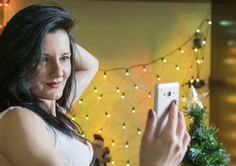 a beautiful brunette girl takes a selfie against the background of christmas lights stock image