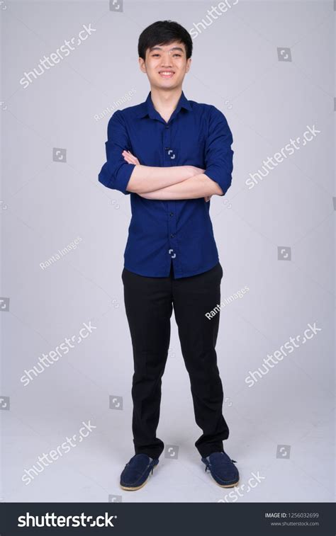 Full Body Shot Of Young Happy Asian Businessman Smiling With Arms