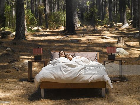 A Couple Sleeping In A Bed Outdoors In The Woods Bildbanksbilder