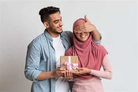 Romantic Arab Lady Hugging Husband Preparing Present And Smiling At Camera Posing Over Yellow