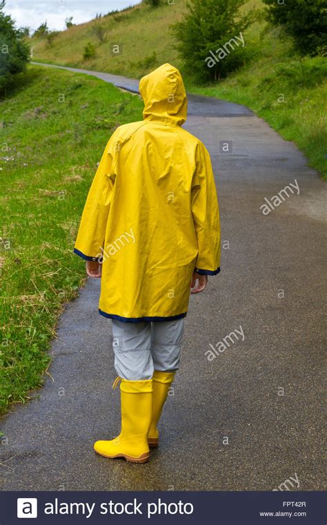 Vivienne getting hot wading in the deep mud. Young woman wearing a yellow raincoat and rubber boots ...