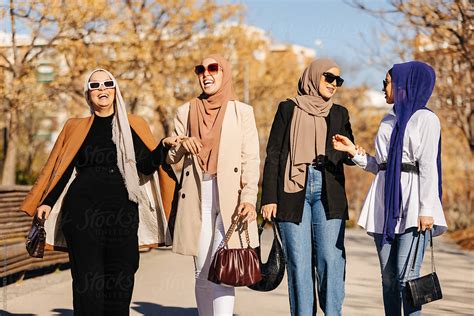 cheerful muslim women in hijab having a walk and talking to each other del colaborador de