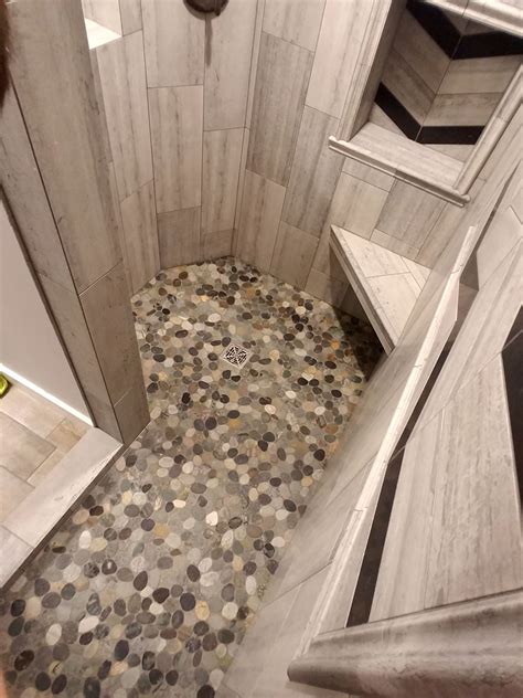We love how the dark grout makes the cream tiles pop along with the golden hardware. Gorgeous shower floor using Sliced Bali Ocean Pebble Tile ...