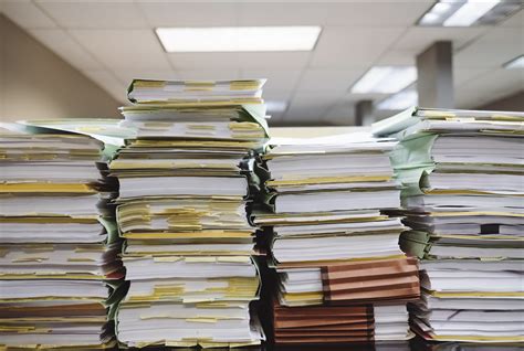 Stacks Of Paper Piled Up On Desk Crest Real Estate