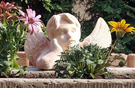 A Statue Of An Angel Surrounded By Flowers