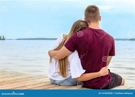 A Young Couple A Girl And A Young Man Sit On The Beach In A Lotus Position On A Wooden Bridge