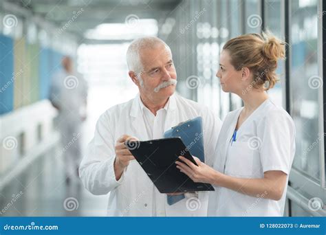 Medical Staff With Clipboard Talking In Hospital Corridor Stock Image