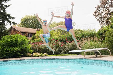 Caucasian Children Jumping Into Swimming Pool Stock Photo Dissolve