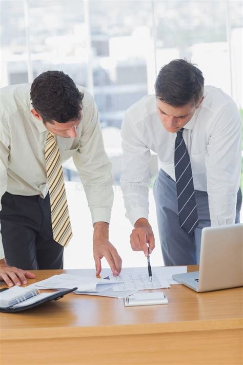Serious Businessmen Working Together Leaning On The Desk Stock Photo