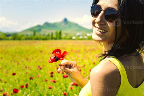 Young Happy Caucasian Brunette Woman Holding Single Poppy Flower And Enjoy Sunny Day In Field