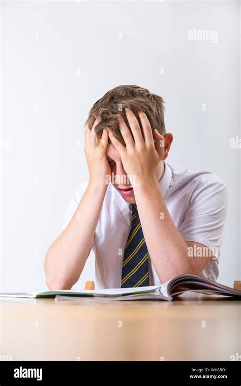 A Stressed School Pupil With His Head In His Hands Sat At His Desk