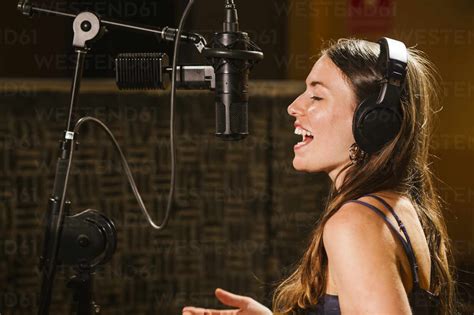 Singer With Headphones At Microphone In Recording Studio Stock Photo