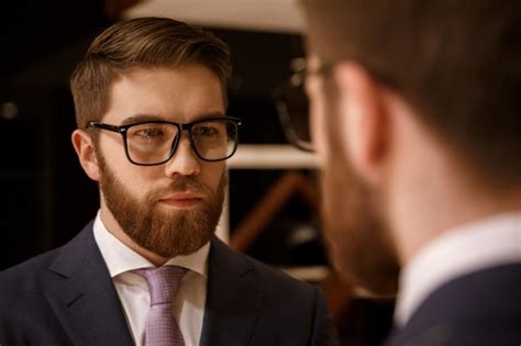 Concentrated Young Bearded Businessman Looking At Mirror Free Photo