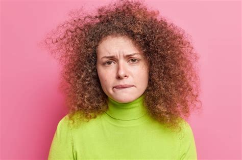 Premium Photo Photo Of Frustrated Unhappy Woman With Curly Hair Bites Lips Looks Nervously