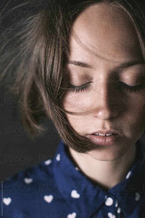 Portrait Of A Young Woman With Closed Eyes Wearing A Blue Shirt With