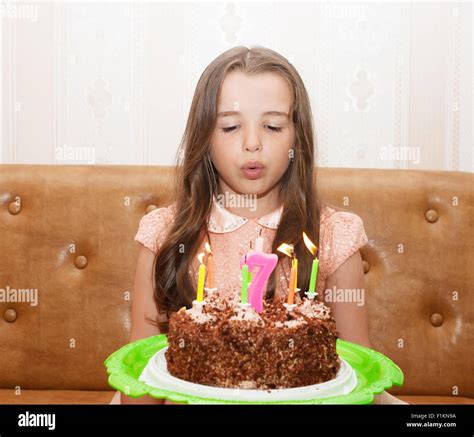 Little Girl 7 Years Old Blowing Out The Candles On A Birthday Cake