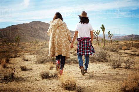Two People Holding Hands And Walking On Desert Stock Photo Dissolve