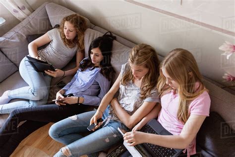 High angle view of teenage girls using technologies while watching TV ...