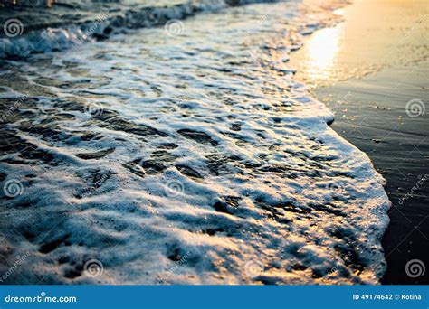 Wave Of The Ocean Sea On The Sand Beach At The Sunset Light Stock