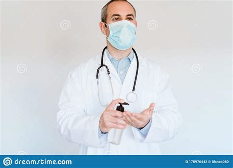 caucasian doctor wearing protective mask and gloves indoors using an alcohol gel or