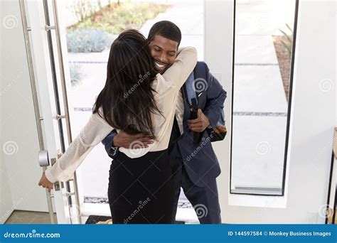el saludo de la mujer y el hombre de negocios husband as he del abrazo vuelve a casa de trabajo