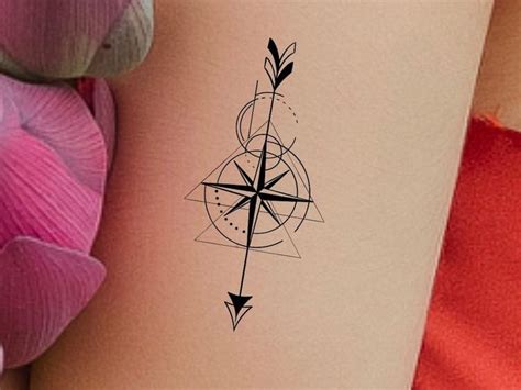 An Arrow Tattoo On The Back Of A Womans Leg Next To Pink Flowers