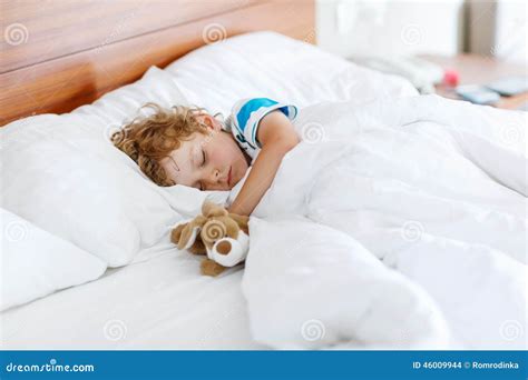 Adorable Kid Boy Sleeping And Dreaming In His White Bed With Toy Stock