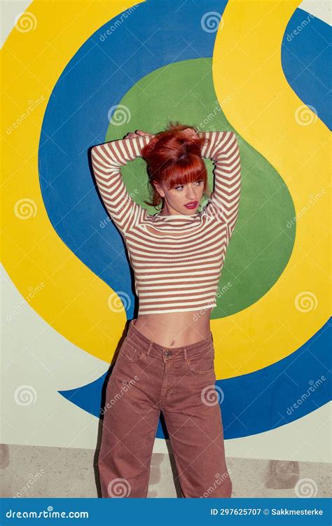 Young Redhead Caucasian Woman In Retro Style Of 70s Posing At Wall