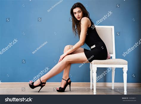 Fashion Model Woman Posing On The Chair Behind The Wall