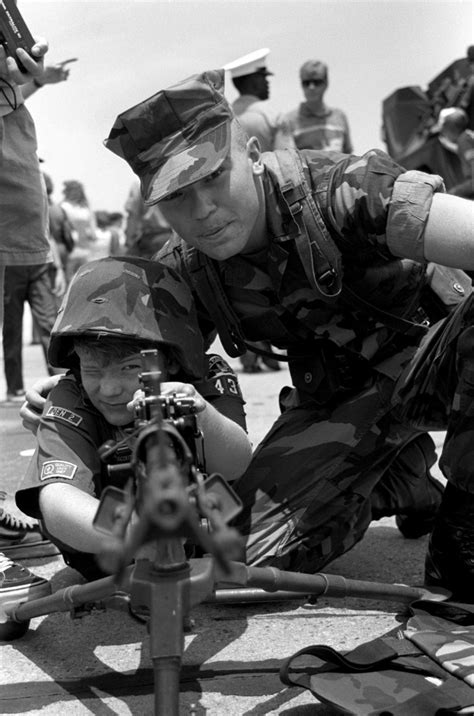 A Marine Demonstrates Use Of A M 60 Machine Gun To A Youngster