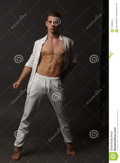 A Guy With A Naked Torso In White Pants And In A White Shirt Stands