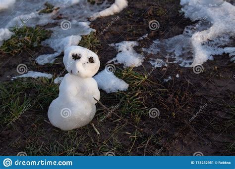 Last Miniature Snowman Standing In Mud And Grass Melting In The