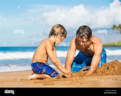 Father And Son Playing Together In The Sand On Tropical Beach Building