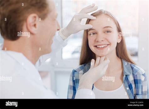 Delighted Dermatologist Examining Patient Skin In The Hospital Stock
