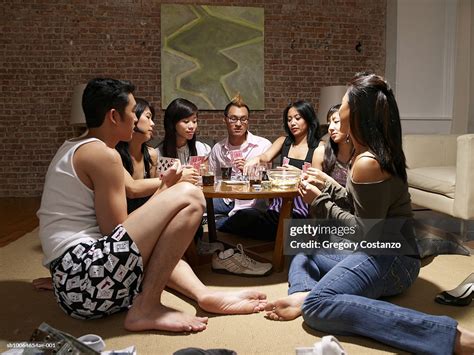 Group Of Friends Sitting On Floor Around Table In Living Room Playing